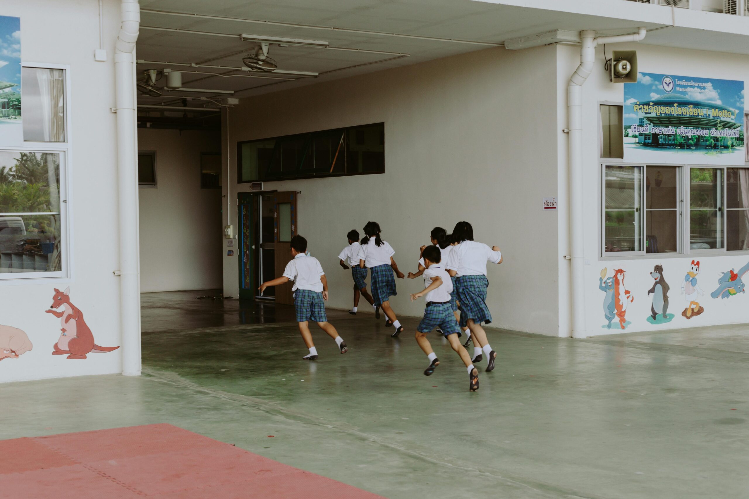 Group of kids in school uniforms running indoors, depicting lively childhood energy.
