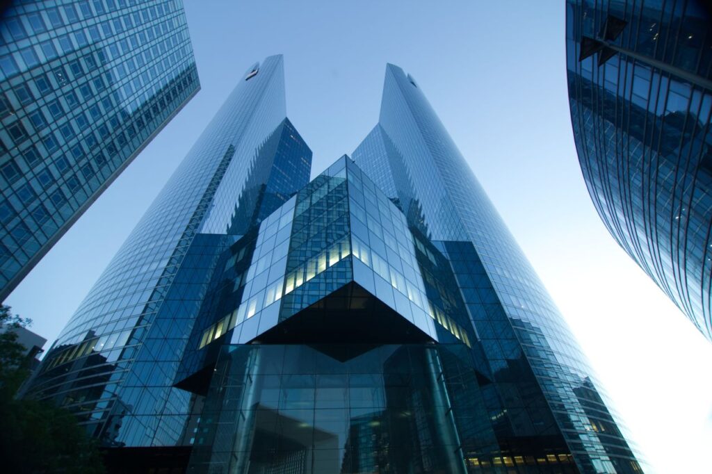 Low-angle view of modern glass skyscrapers reflecting a clear blue sky. Perfect for urban and architectural themes.